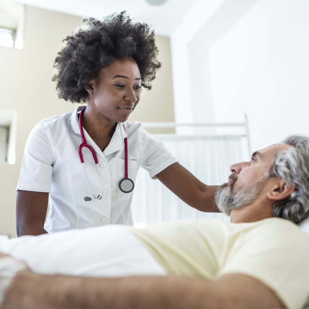 Senior patient on bed talking to African American female doctor in hospital room, Health care and insurance concept. Doctor comforting elderly patient in hospital bed or counsel diagnosis health.