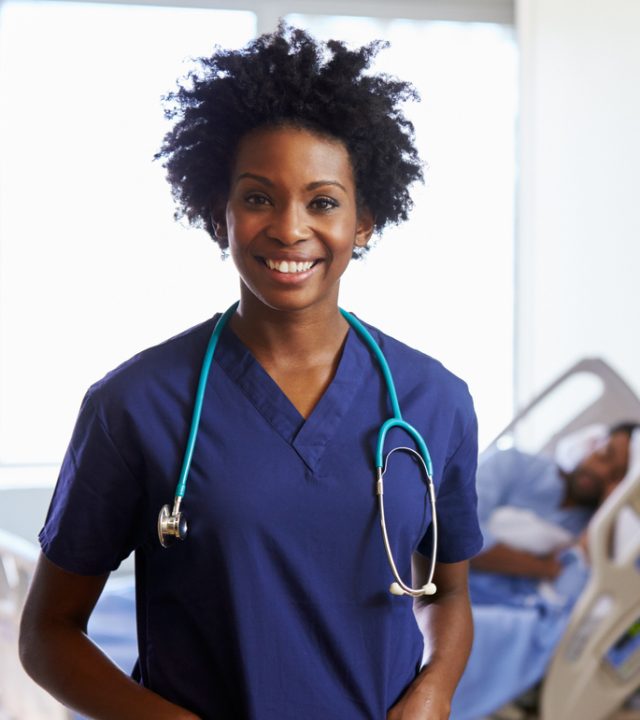 Portrait Of Female Nurse With Patient In Background